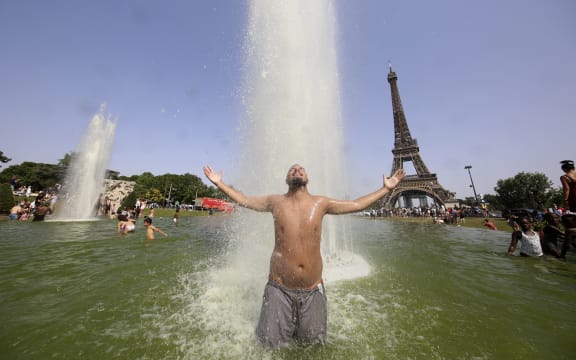 A man cools off in The Trocadero Fountains across from the Eiffel Tower in Paris on 18 June 2022, amid record high temperatures sweeping across France and western Europe.