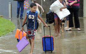 Families leave the Cooktown evacuation centre after taking shelter overnight.