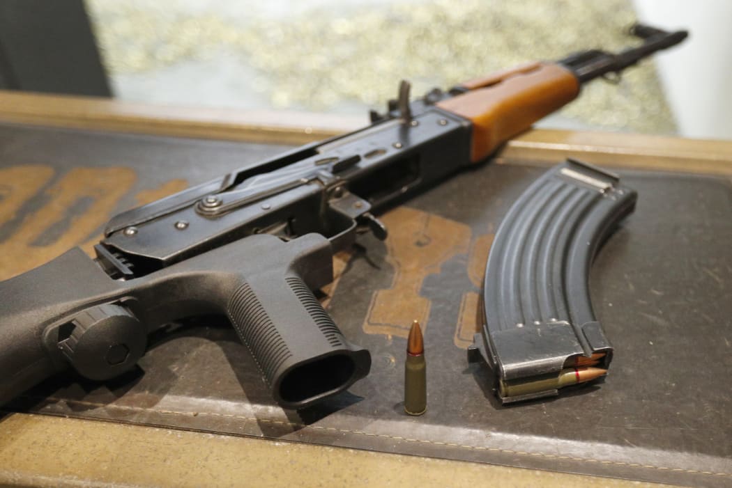 A 7,62X39mm round sits next a a 30 round magazine and an AK-47 with a bump stock installed.