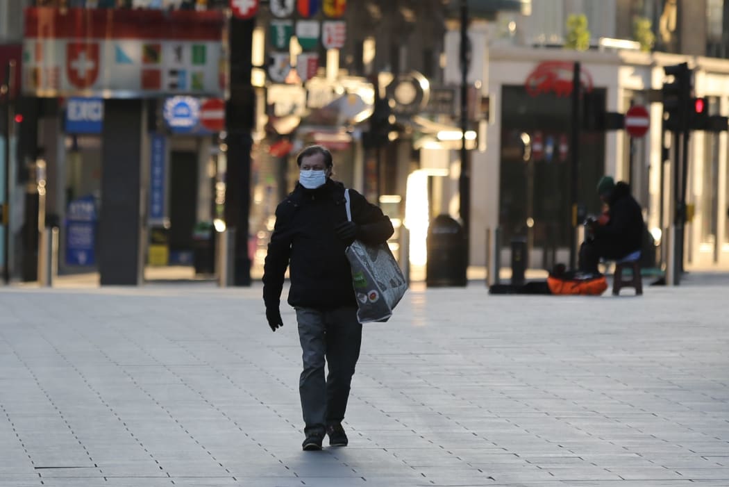 A man wears a medical mask as a precaution against coronavirus at deserted Leicester Square in London, United Kingdom on March 23, 2020.