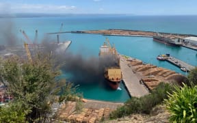The thick black smoke clouds billowing from the ship at Napier Port draws a stark contrast with the clear blue day.