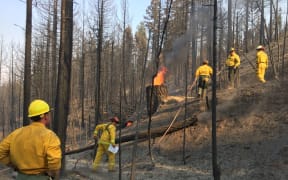 Corporal Thomas Grant supervises US firefighters who are hot-spotting & felling trees as they help battle the Carr Fire in northern California.