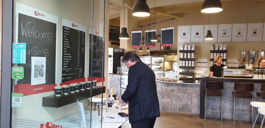 A customer signing in and sanitising their hands before ordering at Adoro Cafe in Napier.