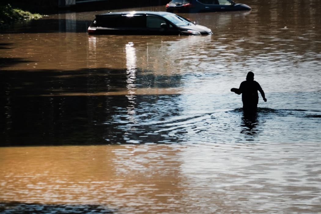 NEW YORK CITY - SEPTEMBER 02: A man walks through a flooded Major Deegan Expressway in the Bronx as dozens of cars and trucks sit abandoned following as night of heavy wind and rain from the remnants of Hurricane Ida on September 02, 2021 in New York City.