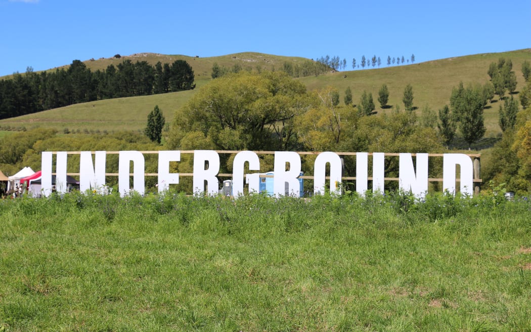 A sign - the word "Underground" in large block lettering sits out in a green field