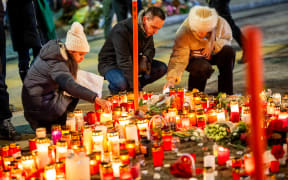 Mourners light candles at a makeshift memorial near the site of a fire that ripped through a bar during New Year's Eve celebrations in the Alpine ski resort town of Crans-Montana killing around 40 people and injuring more than 100 others, in Crans-Montana on January 2, 2026.