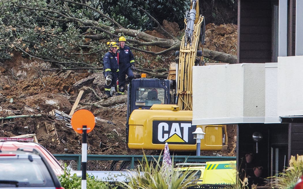 Police and officials stand following a landslide while a search is underway by local emergency services for missing people at Mount Maunganui in Tauranga on January 22, 2026. A landslide smashed into a campsite in rain-swept northern New Zealand leaving multiple people missing, police and rescuers said. (Photo by DJ MILLS / AFP)