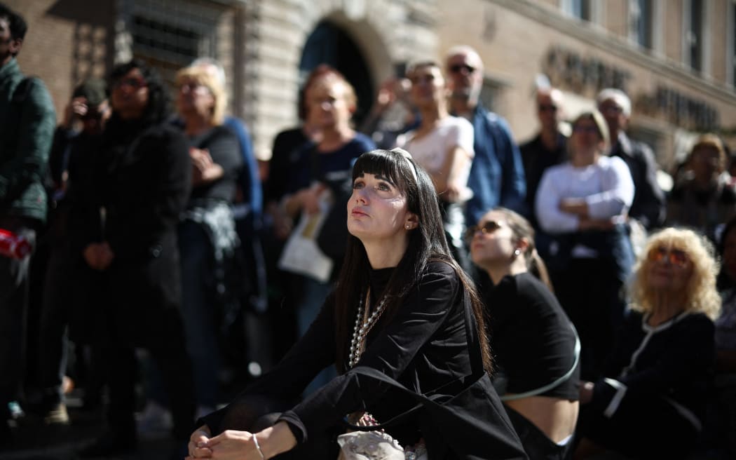 People watch late Pope Francis' funeral ceremony on a large screen in Via della Conciliazione street, near the Vatican in Rome on April 26, 2025. Pope Francis, champion of the poor and the Church's first Latin American leader, will be honoured April 26 with a funeral attended by world leaders and tens of thousands of Catholic faithful. The Argentine pontiff, who died on April 21, 2025, aged 88, sought to create a more open-minded Church during his 12-year papacy, and many emotional tributes have been made -- with 250,000 people paying respects at his coffin in St Peter's Basilica. (Photo by HENRY NICHOLLS / AFP)