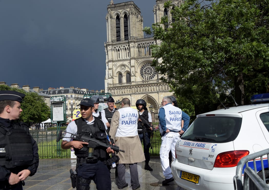 French police officials and investigators gather near the entrance of Notre Dame cathedral in Paris after police shot and injured a man who had tried to attack an officer with a hammer.