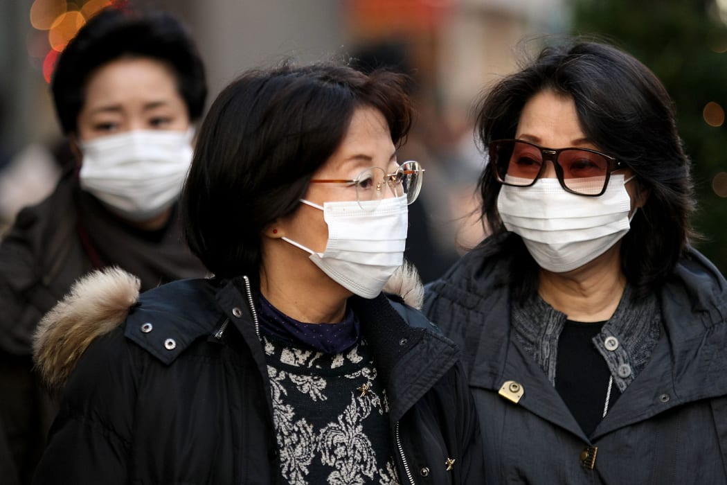 People wearing a mask walks past about the outbreak of coronavirus in Wuhan, China at Ginza shopping district in Tokyo, Japan, January 26, 2020.  (Photo by Hitoshi Yamada/NurPhoto)