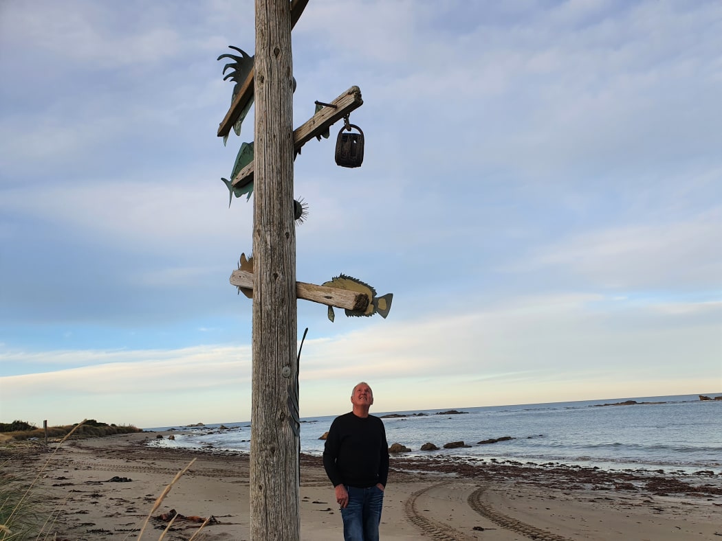 Jeff Burnett with his art piece which helps guide boaties into the bay.