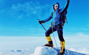 Johnny Ward stands on the top of a snow covered mountain.