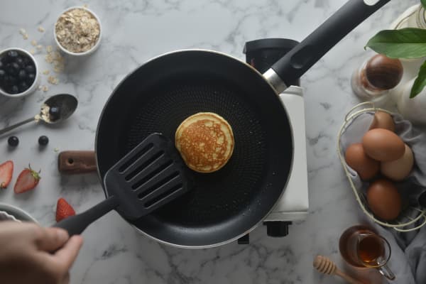 Flip the pancakes with a spatula. Concept of Cooking ingredients and method on white marble background, Dessert recipes and homemade.