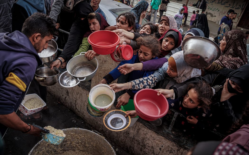 12/28/2023 Gaza, Palestine. Palestinians wait to collect food at a donation point in a refugee camp in Rafah in the southern Gaza Strip on December 23, 2023, amid continuing battles between Israel and the militant group Hamas. (Photo by Saher Alghorra / Middle East Images / Middle East Images via AFP)