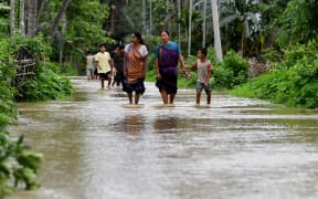 Villagers wade through a flooded street after heavy rains in Kampur at Nagaon district, in India's northeastern state of Assam on June 1, 2025. Flash floods and landslides after torrential monsoon rain over the last two days killed at least 30 people in India's northeast, officials said on June 1. (Photo by Biju BORO / AFP)