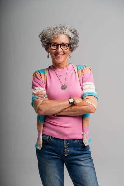 Denise Quinlan standing smiling with arms folded.