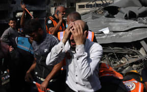 A Palestinian man reacts as the body of his daughter is unearthed from rubble after an Israeli strike on Rafah in the southern Gaza Strip on 22 October, 2023.