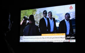 An Egyptian woman watches the news on a local channel in Cairo on October 8, 2025, showing images of the US president's Middle East envoy Steve Witkoff (R) and son-in-law Jared Kushner (C) arriving in Sharm El-Sheikh for talks on ending the Gaza war.