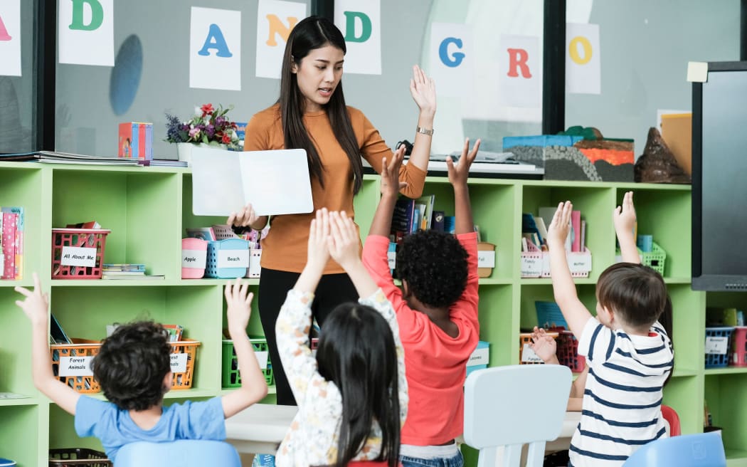 Young asian woman teacher teaching kids in kindergarten classroom, preschool education concept