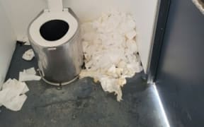 Photo of a DOC toilet with toilet paper piled up