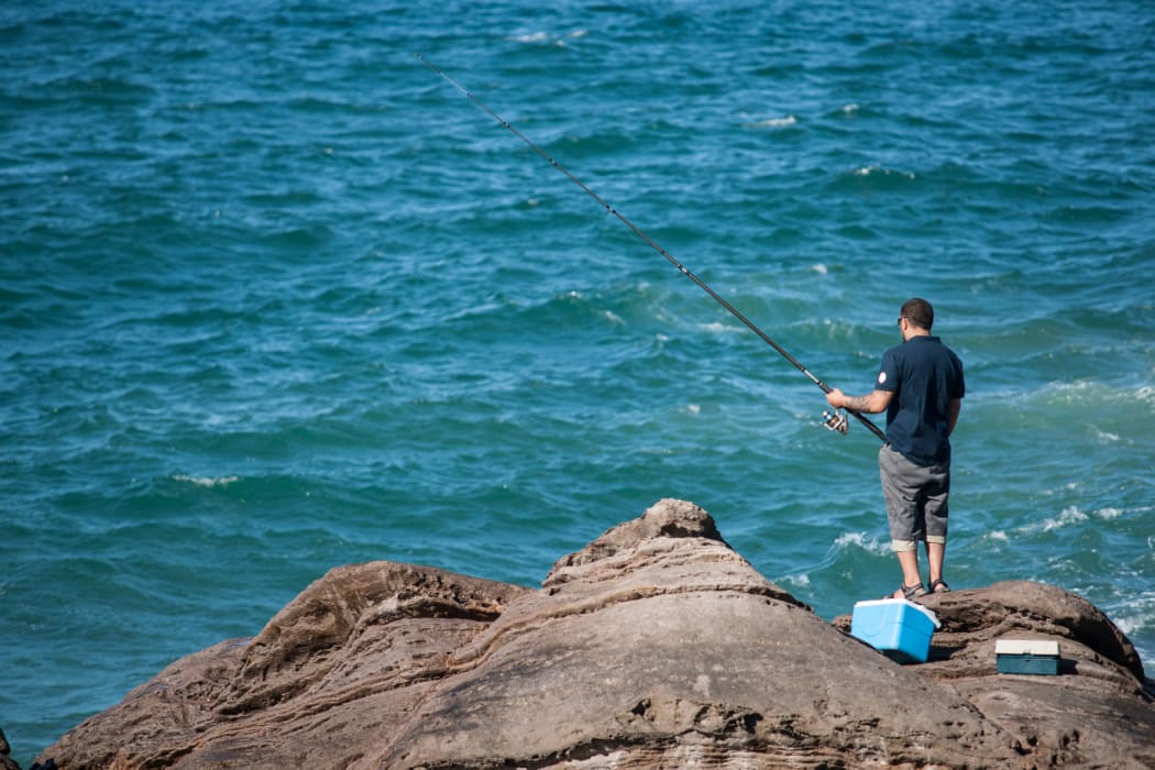 Man rock fishing at base of Mount Maunganui.