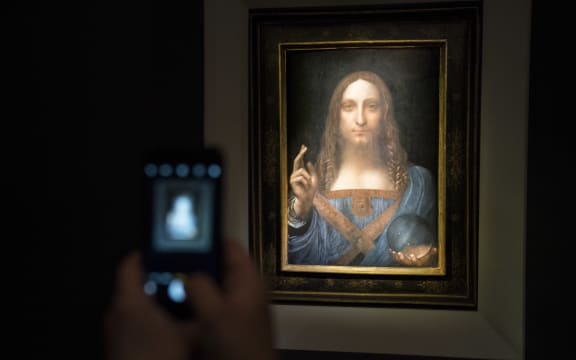 A visitor takes a photo of the painting 'Salvator Mundi' by Leonardo da Vinci at Christie's New York Auction House, November 15, 2017 in New York City.