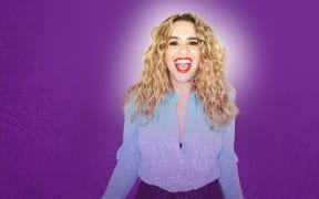 The promotional poster for Michelle Brasier's show REFORM. She stands in front of a purple background smiling.