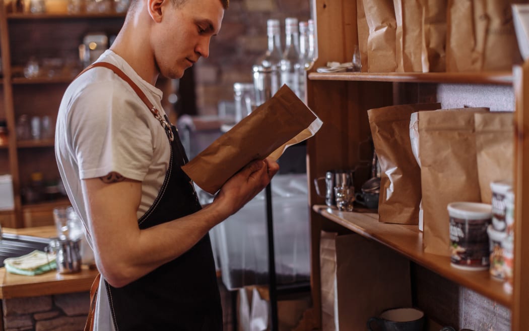 male barista is holding a package with coffee