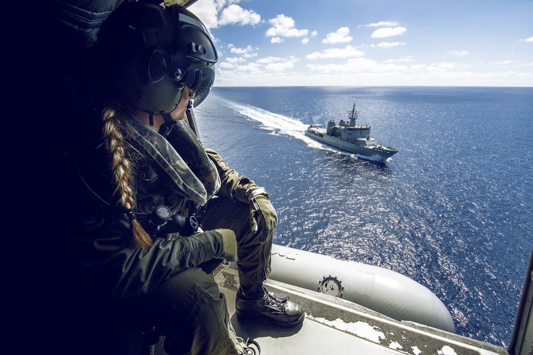 Leading Helicopter Loadmaster Steph Roberts watches HMNZS Wellington as the 6SQN SH-2G(II) Seasprite Helicopter flies nearby.