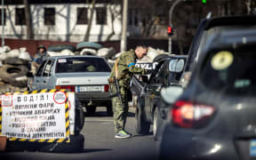 A member of the Ukrainian Territorial Defence Forces checks cars at a checkpoint in Kyiv, on March 20, 2022.