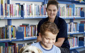 Connor reads to Charlie Brown, a shih tzu cross, while animal control manager Megan May looks on.