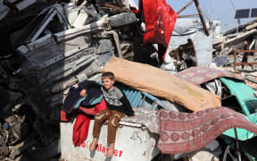 A displaced Palestinian child sits outside his family's tent in the Jabalia refugee camp in the north of the Gaza Strip on January 6, 2026.