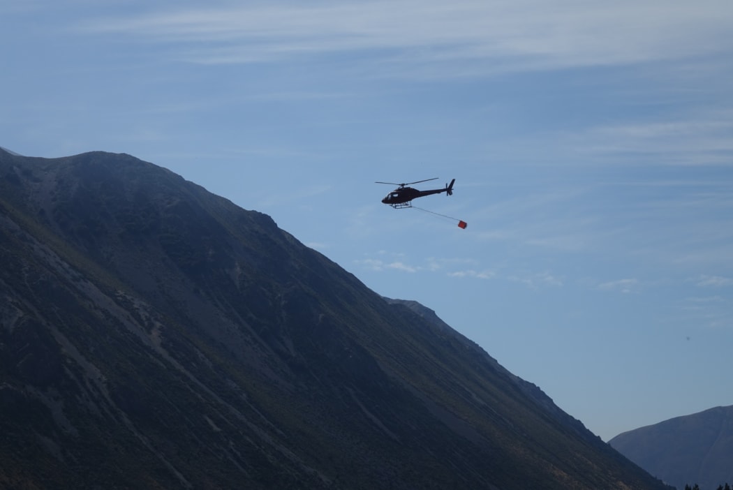 A helicopter with a monsoon bucket fights the fire near Craigieburn Forest Park.