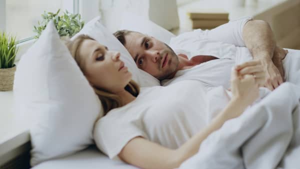 Man looks to woman in bed who is pondering.