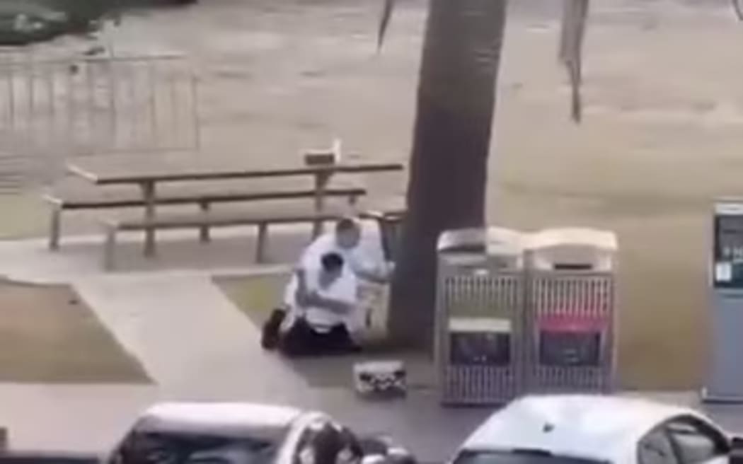 The two men crouch behind a tree as shots ring out.