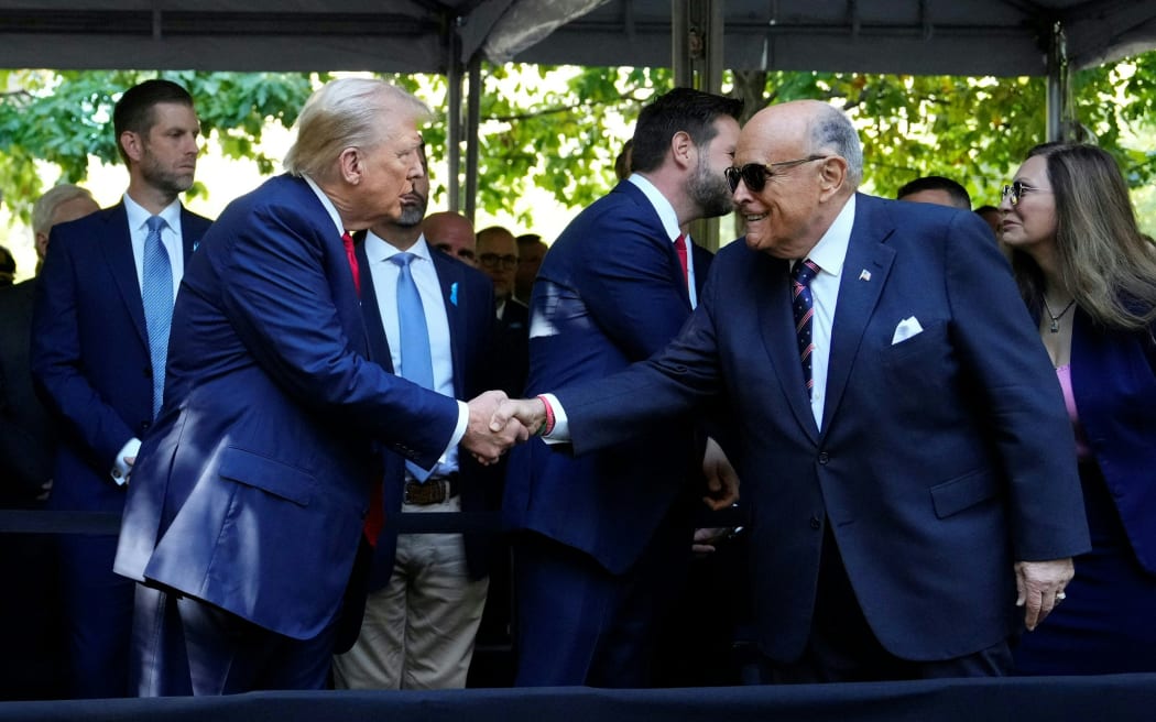 Former US President and Republican presidential candidate Donald Trump (L) shakes hands with former New York City Mayor Rudy Giuliani  during a remembrance ceremony on the 23rd anniversary of the September 11 terror attack on the World Trade Center at Ground Zero, in New York City on September 11, 2024. (Photo by Adam GRAY / AFP)