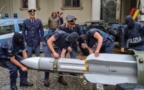 Italian policemen carry an air-to-air missile, as part of a big cache of guns and ammunition that was seized by the Turin special police force