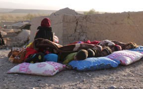 Afghan children rest under a blanket beside damaged houses after earthquake in Sarbuland village of Zendeh Jan district of Herat province on October 7,2023 (Photo by Mohsen KARIMI / AFP)