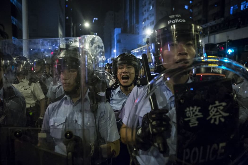 A police officer yells instructions during a protest against an expected interpretation of the city's constitution, the Basic Law, by China's NPCSC.