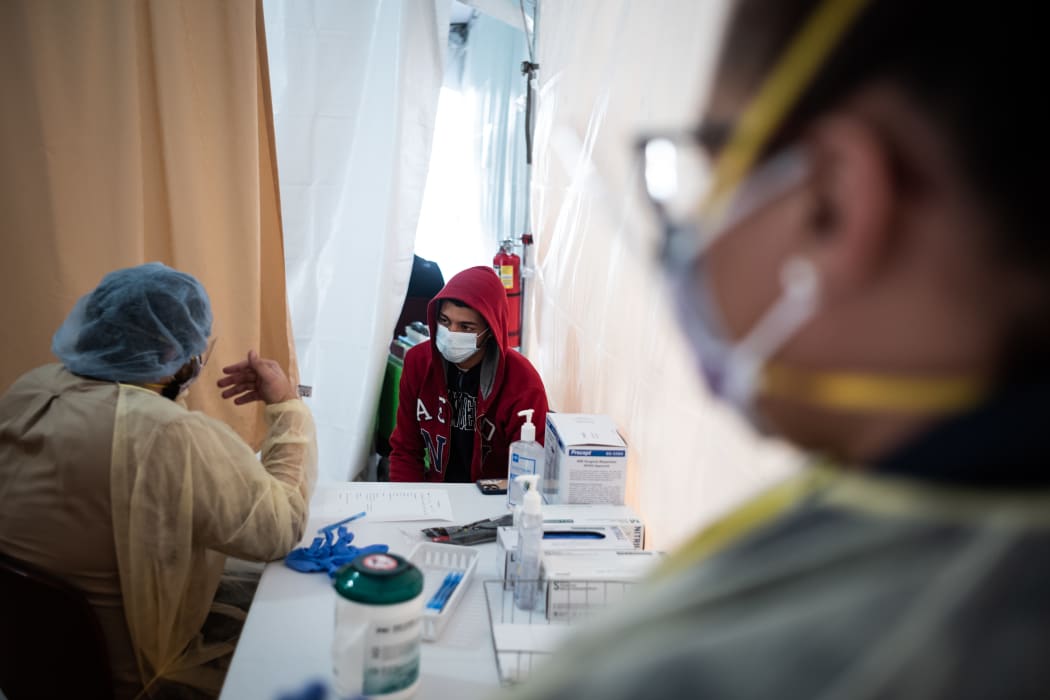A doctor examines a patient for a Covid-19 test inside a testing tent outside a New York hospital.
