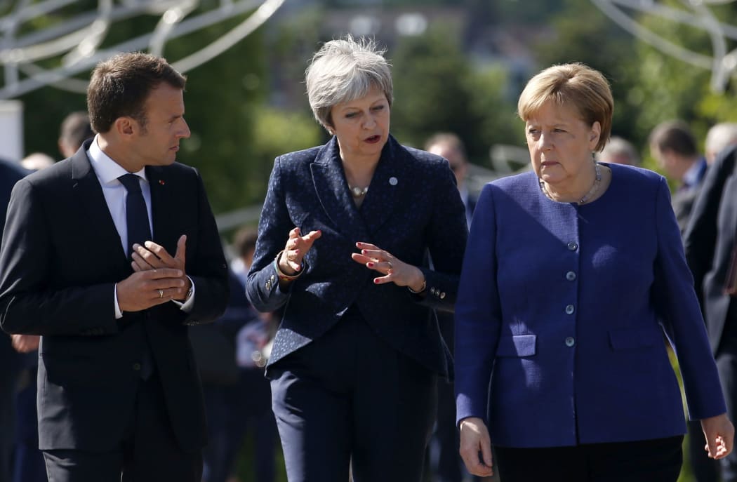 FILE - In this Thursday, May 17, 2018 file photo German Chancellor Angela Merkel, right, speaks with French President Emmanuel Macron, left, and British Prime Minister Theresa May