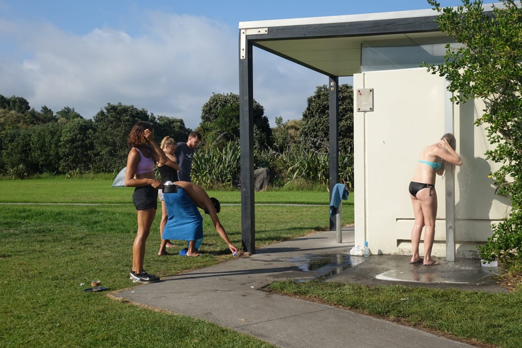 Travellers line up for the one outdoor shower at Waiwhakaiho.