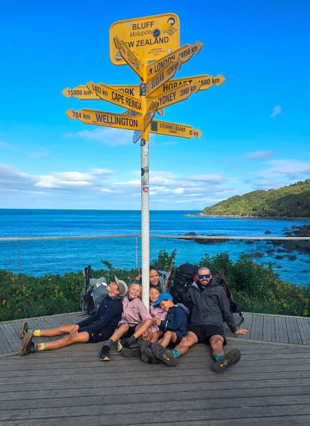 The Williams family sits near a sign at Stirling Point, Bluff, the end of the Te Araroa trail. 