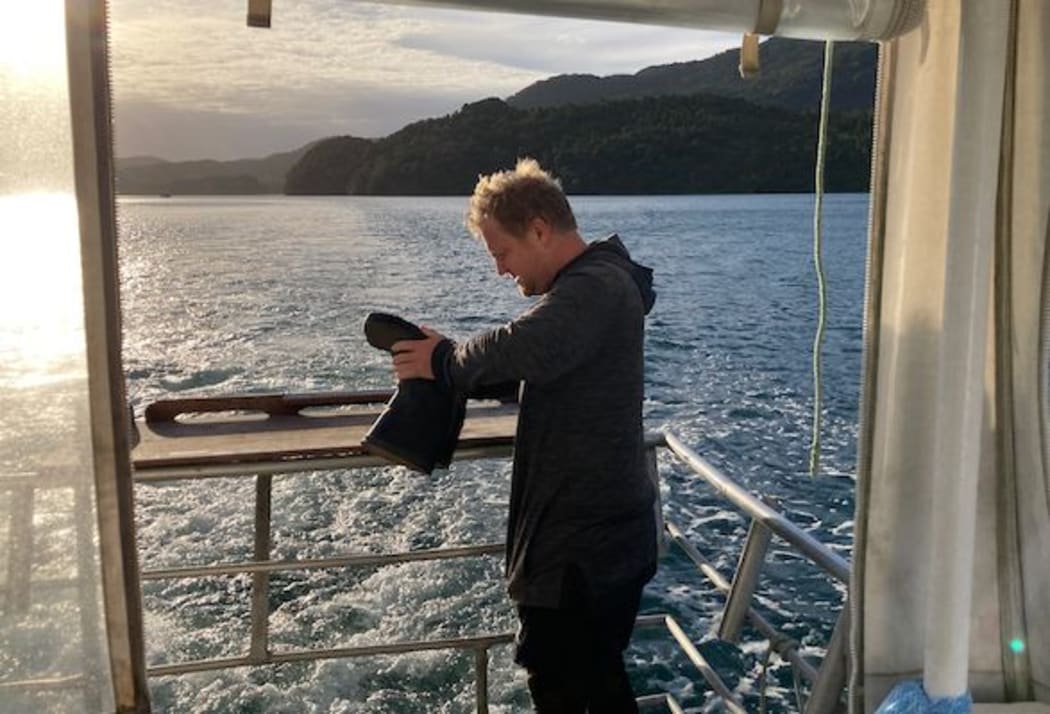 Expedition director Willy McKee empties a gumboot after a shore sortie.