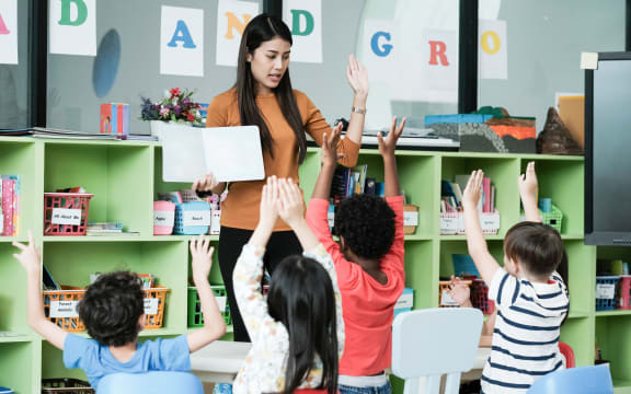 Young asian woman teacher teaching kids in kindergarten classroom, preschool education concept