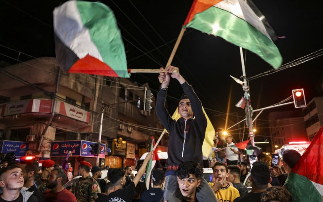 Palestinians and supporters of the Islamic Jihad militant group celebrate in the street after Palestinian factions and Israel reached a ceasefire agreement in Gaza City on May 13, 2023.