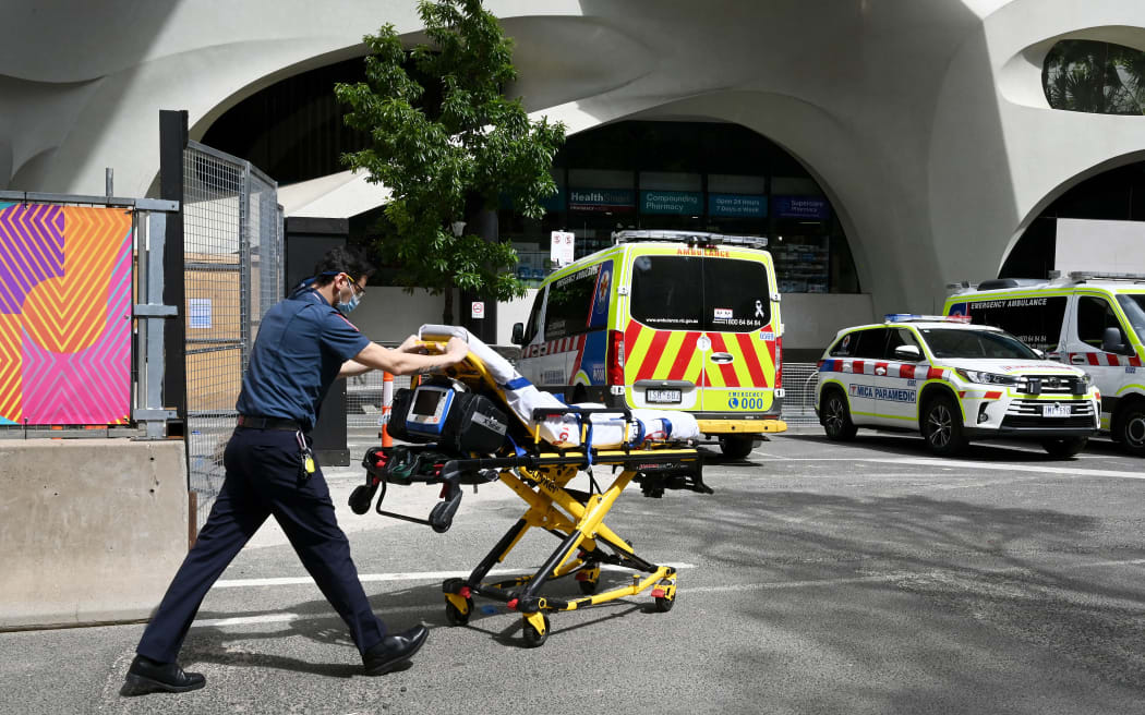 A paramedic pushes a bed towards his ambulance in Melbourne on October 9, 2021, as Victoria state recorded 1965 new Covid cases, its highest daily infection number since the start of the pandemic, putting more pressure on the state's struggling health system. (Photo by William WEST / AFP)