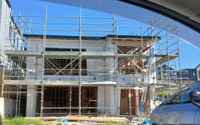 A partially-built house, with scaffolding and framing erected.