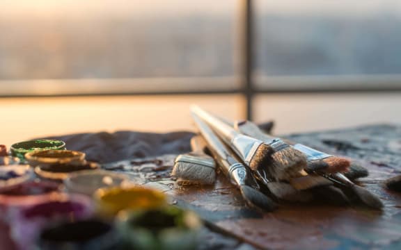 Drawing classes tools in art studio. angle view photo of paintbrushes lying on palette with oil paints brushstrokes mixture