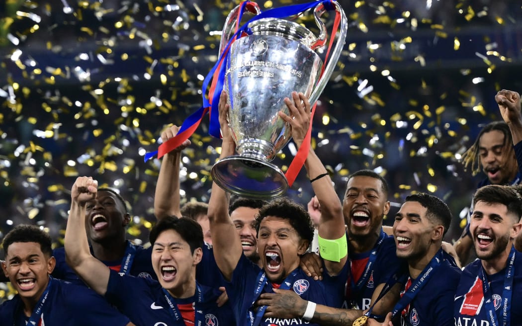 Paris Saint-Germain's Brazilian defender #05 Marquinhos lifts the trophy next to his teammates after the UEFA Champions League final football match between Paris Saint-Germain (PSG) and Inter Milan in Munich, southern Germany on May 31, 2025. (Photo by Marco BERTORELLO / AFP)